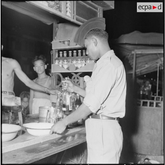 51 Un jeune militaire cambodgien s'apprête à se servir un verre au comptoir d'un bar. [description provisoire]