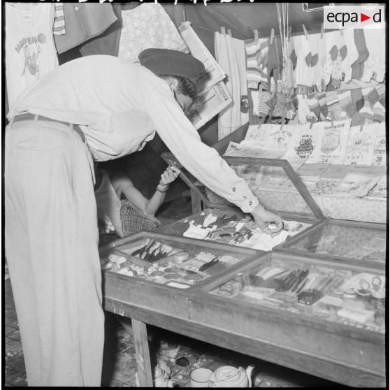 52 Un jeune militaire cambodgien choisit une marchandise à un comptoir. [description provisoire]