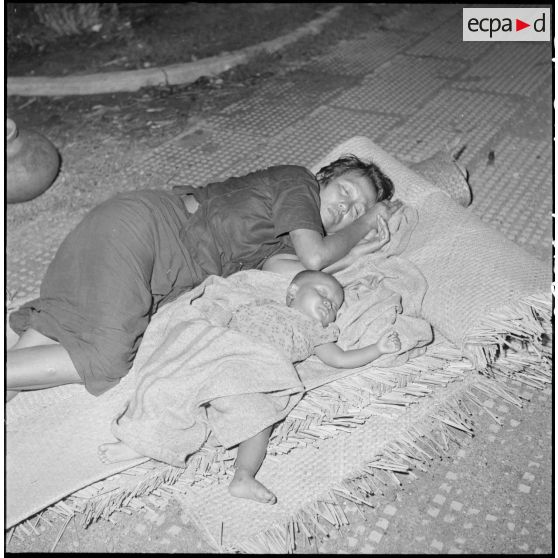 60 à 64 Cambodgiens dormant sur des nattes dans la rue, la nuit. [description provisoire]