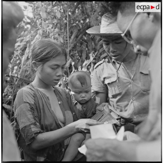 Un commando franco-vietnamien contrôle les papiers d'une femme trouvée dans la végétation avec son bébé au cours de l'opération Jeanne d'Arc. [description provisoire]