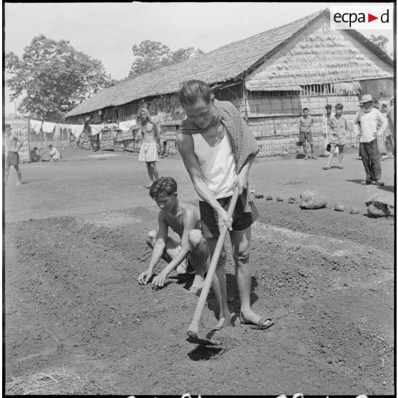 Deux prisonniers entretiennent le jardin du camp de Kompong Cham. [description provisoire]