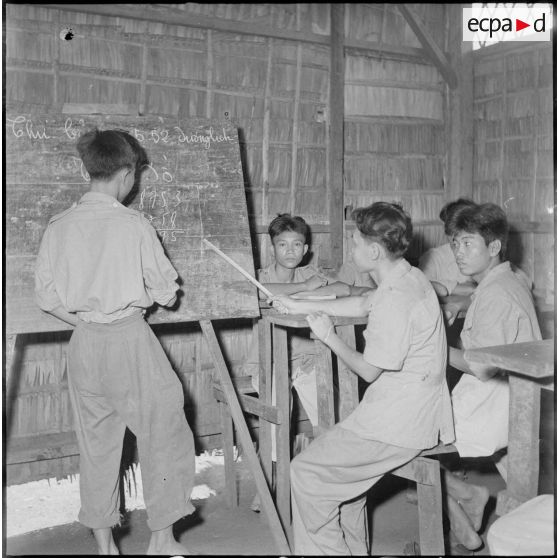 A l'école du camp de Kompong Cham, les jeunes prisonniers étudient sous la direction de leur maître. [description provisoire]