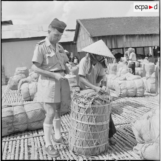 Un capitaine d'administration d'intendance vérifie la qualité du poisson emballé destiné à l'armée française. [description provisoire]
