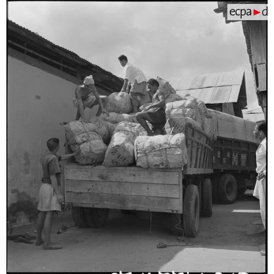 Chargement et départ d'un convoi de camions remplis de ballots de poissons séchés destinés à l'armée française. [description provisoire]