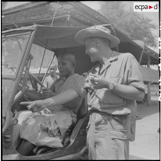 103 Bonze assis aux commandes d'une jeep près de laquelle se trouve son conducteur ; un autre bonze en arrière-plan. [description provisoire]