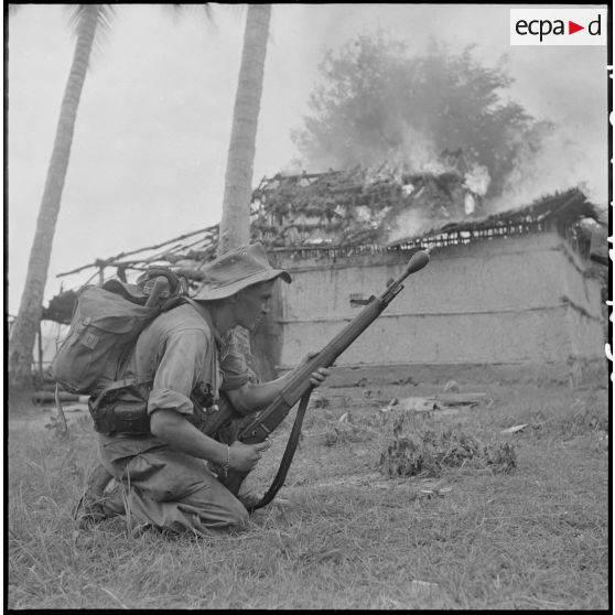 30 Le première classe Morvan, armé d'un fusil lance-grenades, devant un PC du Viêt Minh en flammes. [description provisoire]