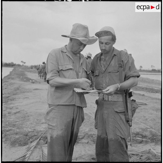 Le lieutenant Caraux (à droite) expose ses projets sur la carte au reporter photographe Gahéry. [description provisoire]