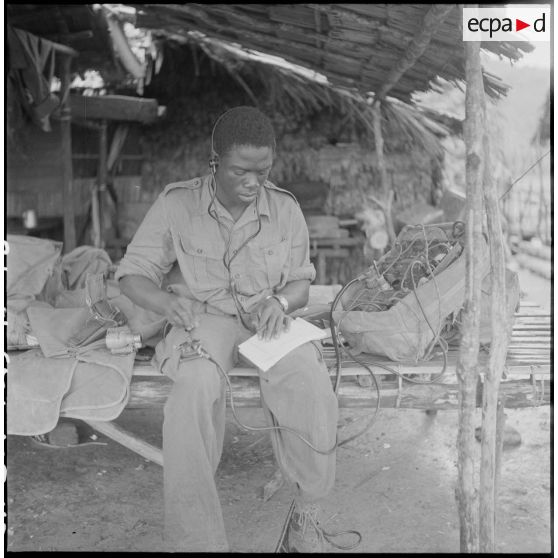 48 Au bivouac, le caporal Tréloué, de Côte d'Ivoire, opérateur radio, transmet par radio le compte rendu de la matinée. [description provisoire]