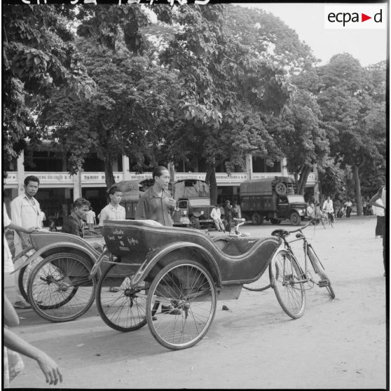 Des cyclo-remorques à l'arrêt dans une rue de Pursat. [description provisoire]