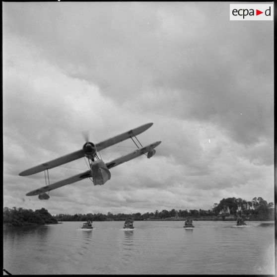 Convoi de vedettes blindées du 4e régiment de dragons survolées par un hydravion sur la rivière de Saigon. [description provisoire]