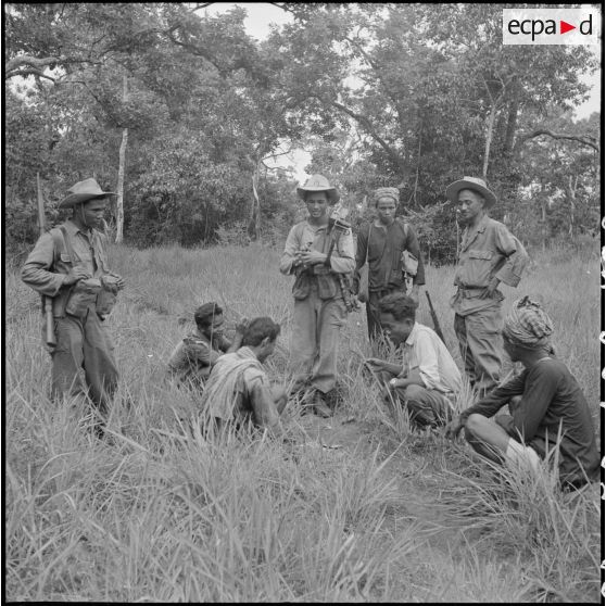 Aidés par un interprète, une section du 3e BCC (Bataillon de Chasseurs Cambodgiens) interroge des bûcherons rencontrés pendant une marche, lors de l'opération ""Sirocco"". [description provisoire]