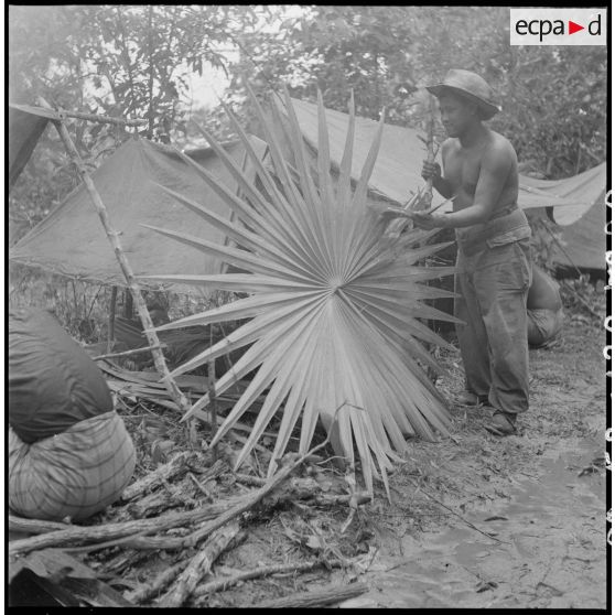 Lors de l'opération "Sirocco", un première classe de l'Etat-Major du 3e BCC (Bataillon de Chasseurs Cambodgiens) a dévoilé ses sens artistiques en construisant cette rosace végétale pour se mettre à l'abri de la pluie. [description provisoire]