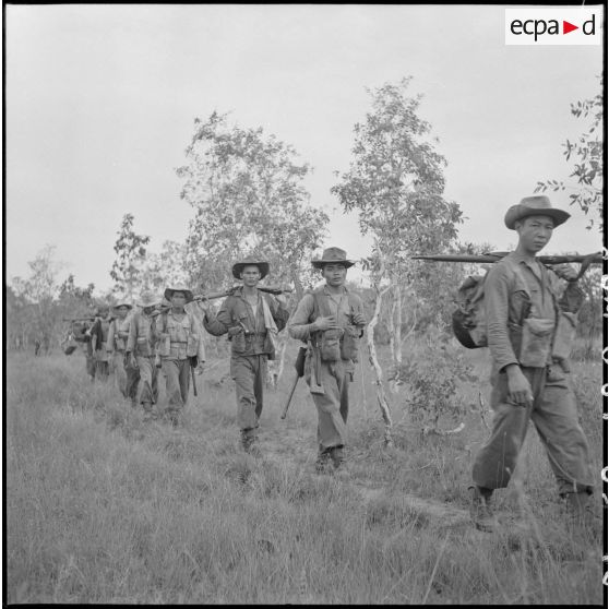 Progression en colonne d'une section du 3e BCC (Bataillon de Chasseurs Cambodgiens) dans une clairière lors de l'opération ""Sirocco"". [description provisoire]