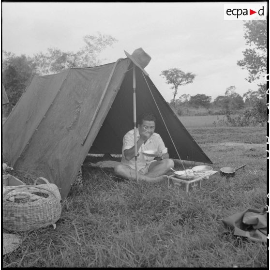 M. Norodom Sihanouk, roi du Cambodge, se restaure à l'entrée de sa tente lors d'une opération militaire menée sous son commandement.. [description provisoire]