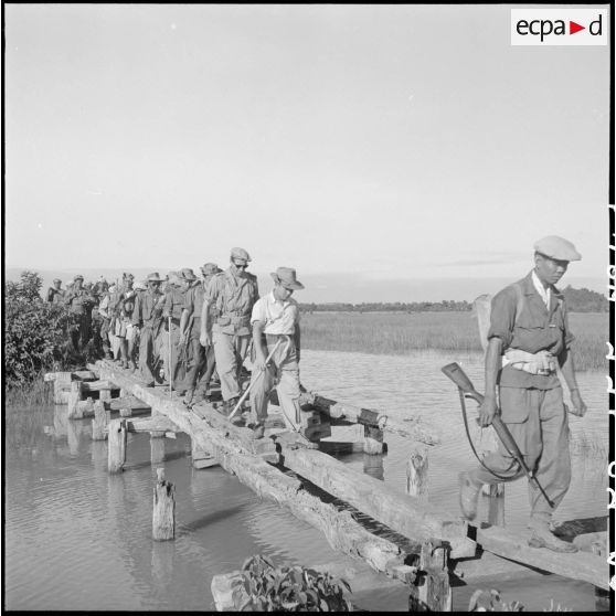 41 à 43 Le roi du Cambodge, traverse un pont de fortune sur la piste de Kralanh Mong, suivi du capitaine Hogart. [description provisoire]