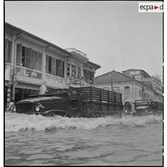 Passage d'un convoi de camions GMC dans la rue Ohier à Phnom Penh, après le passage d'un typhon. [description provisoire]