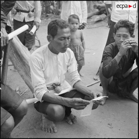 Lecture d'un document distribué par l'armée française au cours d'une tournée de propagande dans la région de Kampot.