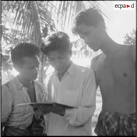 Lecture d'un document distribué par l'armée française au cours d'une tournée de propagande dans la région de Kampot.