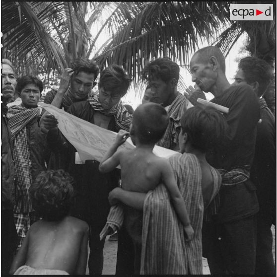 Lecture d'un document distribué par l'armée française au cours d'une tournée de propagande dans la région de Kampot par un groupe d'agriculteurs cambodgiens.