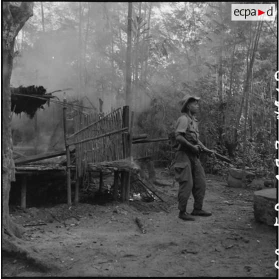 18 Sous la surveillance des guetteurs, les paillotes du cantonnement viêt minh sont fouillées et détruites. [description provisoire]