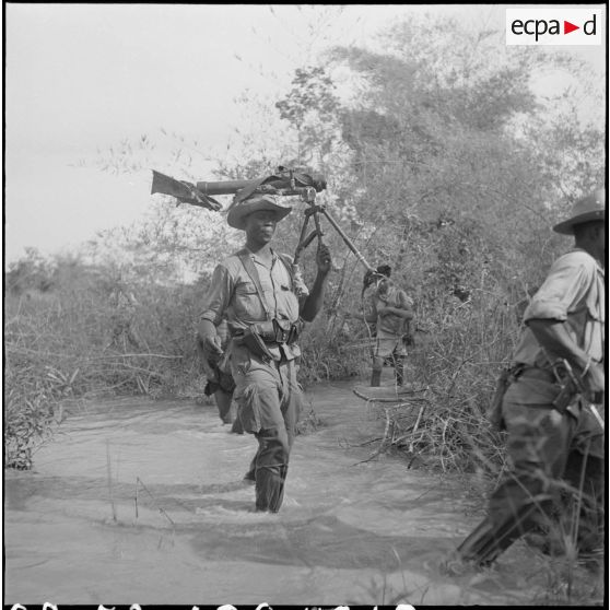 Un mortier de 60mm est transporté de façon inhabituelle par un tirailleur du 2/6e RIC (2e bataillon du 6e Régiment d'Infanterie Coloniale). [description provisoire]