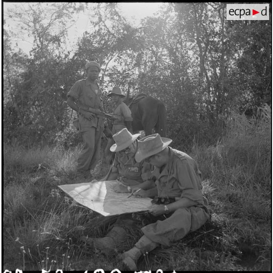 21 Au cours d'une halte, le général Girot de Langlade et le commandant Besson consultent la carte, sous la protection. [description provisoire]