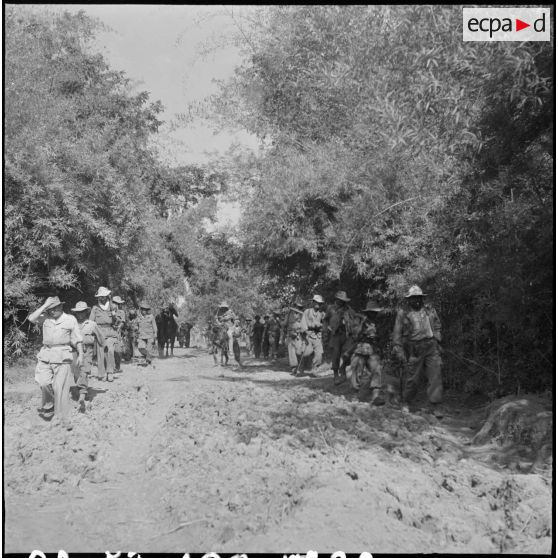 22 Progression d'une colonne des deux côtés d'une route et traversée d'un bourbier desséché. [description provisoire]