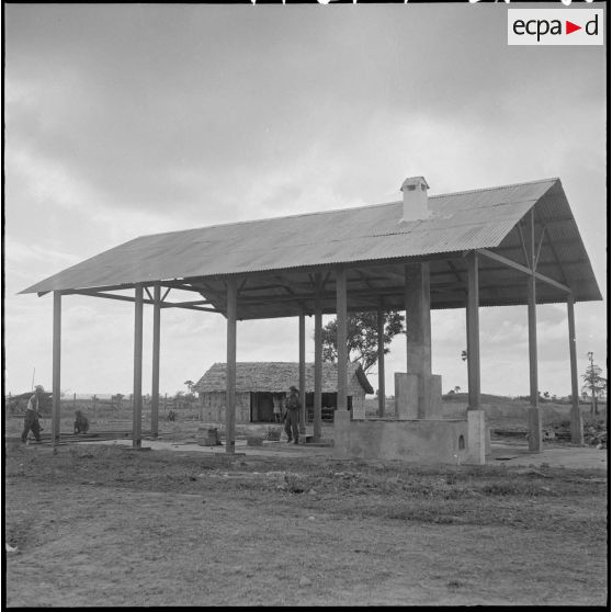 Construction du cantonnement du BSPP (Bataillon de Sécurité de Phnom Penh) : la structure en forme d'auvent abritant les cuisines est terminée. [description provisoire]