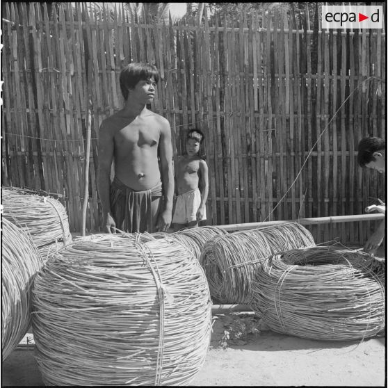 Des jeunes khas préparant des ballots de rotin au poste cambodgien de Voeung Sai. [description provisoire]
