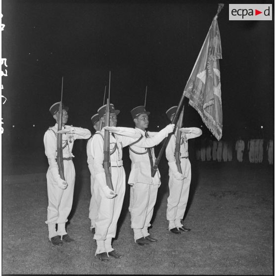 10 A l'arrivée au triomphe, le drapeau de l'Ecole des officiers présentés par un piquet d'honneur, de nuit. [description provisoire]
