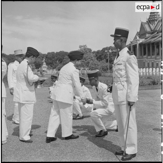 5 Le roi du Cambodge, M. Norodom Sihanouk, remet les épaulettes d'officier à l'un des élèves de la promotion "Ly Yoeun". [description provisoire]