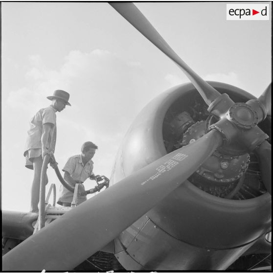 1 Plan rapproché sur le nez d'un avion Bearcat F8F. Deux militaires font le plein d'essence. [description provisoire]