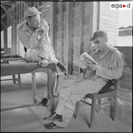 14 Deux pilotes attendent l'ordre du départ en mission. L'un des deux, assis, est en train de lire. [description provisoire]