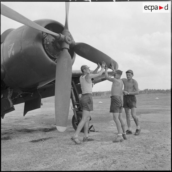 16 Trois mécaniciens font tourner l'hélice d'un avion Bearcat F8F en vue du départ. [description provisoire]