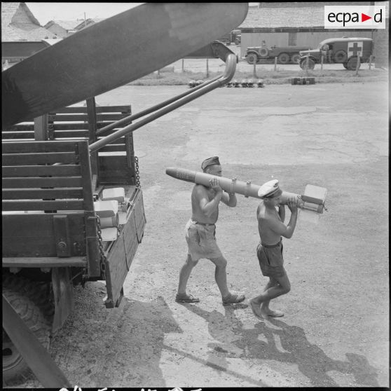 5 à 7 Deux armuriers fixent sous l'aile d'un avion Bearcat F8F une roquette amenée par camion. [description provisoire]