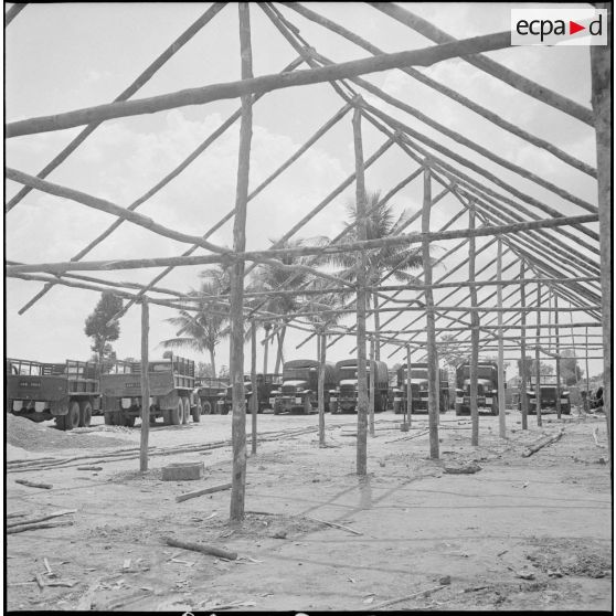 6 Cantonnement en cours de construction : l'armature des charpentes laissent voir les camions GMC 6X6 en arrière-plan. [description provisoire]