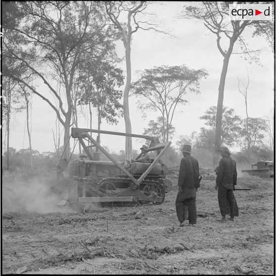 18 à 19 Travaux de terrassement et de nivellement du terrain avec un scrapper, dans la région de Damber - Chong Chéach. [description provisoire]