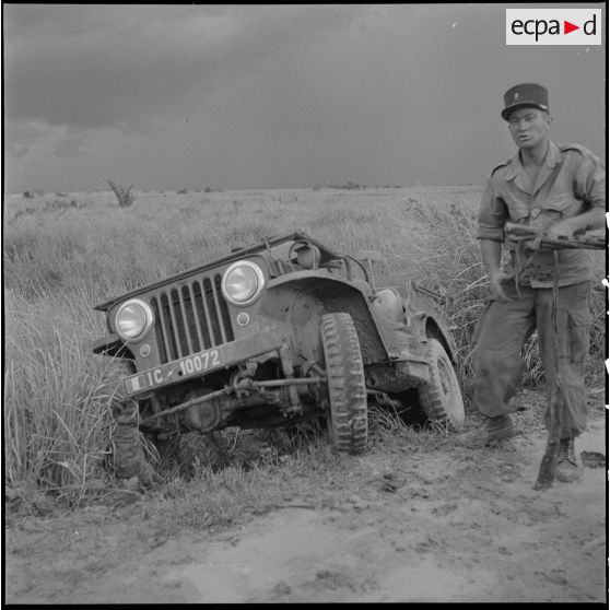 13 à 14 Des militaires de la CMRLE réparent une jeep qui a dérapé. [description provisoire]