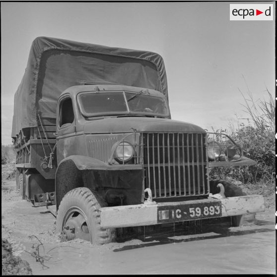 Camion GMC (General Motors Corporation) de la 1re CMRLE (Compagnie Moyenne de Réparation de la Légion Etrangère) franchissant une dérivation inondée par les pluies qui ont commencé, probablement sur la route de Prey Veng. [description provisoire]