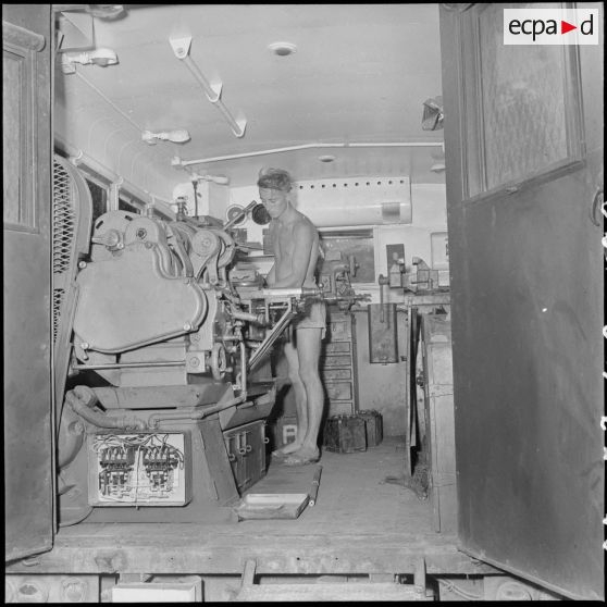 8 à 9 Militaires effectuant une réparation dans un camion "atelier". [description provisoire]