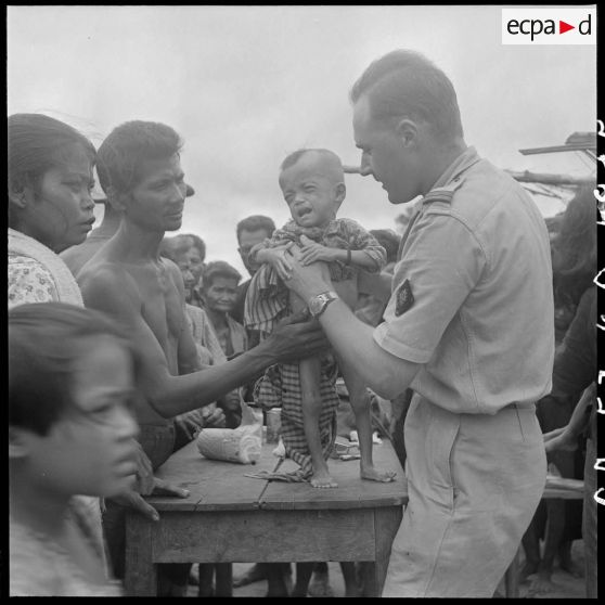 Le médecin-lieutenant Outters du 2/6e RIC (2e bataillon du 6e Régiment d'Infanterie Coloniale) soigne un petit enfant dans un village cambodgien de la province de Kampot. [description provisoire]