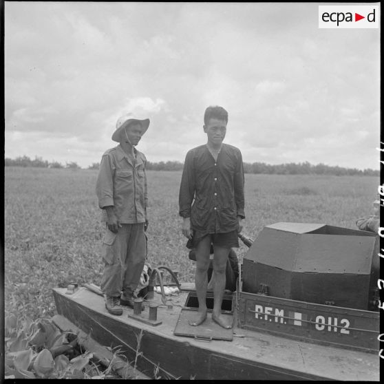 14 Prisonnier, debout sur le  bord de la vedette PFM 0112, gardé par un militaire cambodgien. [description provisoire]