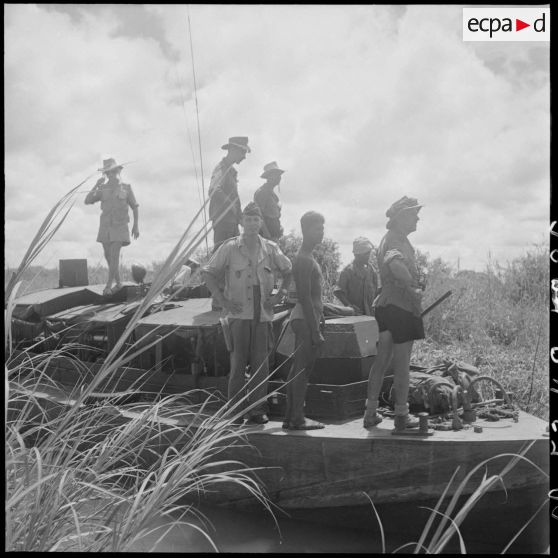 26 Le commandant Delassus Saint Genès, commandant l'opération "Seine I", à bord d'une vedette, entouré de militaires. [description provisoire]