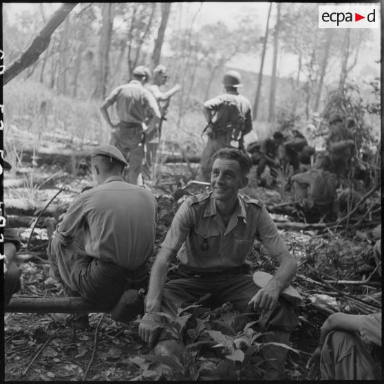 31 Le capitaine de La Touche assis par terre, la mission terminée ; à ses côtés, un groupe de militaires vus de dos. [description provisoire]