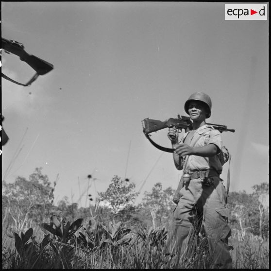 36 Plan rapproché sur un soldat portant sur son épaule un FM M-24/29, en marche sur le chemin de retour. [description provisoire]
