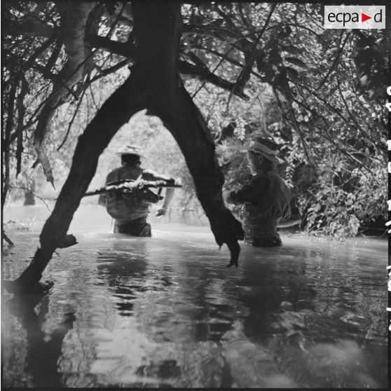 Progression des militaires du 1/RMC (1er bataillon du Régiment Mixte du Cambodge) dans un petit cours d'eau lors d'une patrouille de reconnaissance. [description provisoire]