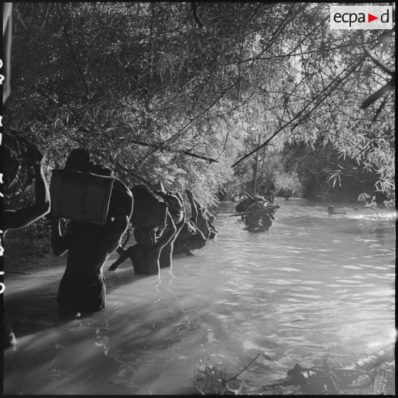 12 à 14 Progression des militaires du commando dans un petit cours d'eau, avec de l'eau jusqu'au ventre. [description provisoire]