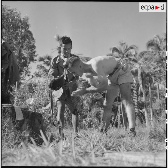 30 à 31 Le lieutenant Balet du Commando de Cholon fait un brin de toilette, aidé d'un militaire cambodgien. [description provisoire]