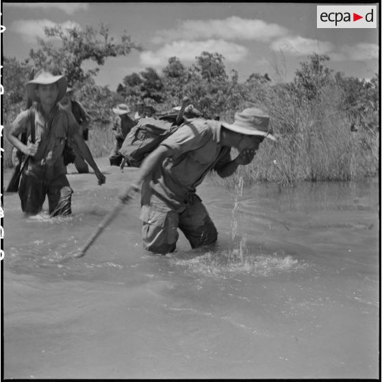 32 à 33 Deux tirailleurs, chargés de leur harnachement, se désaltèrent dans l'eau d'une rivière. [description provisoire]