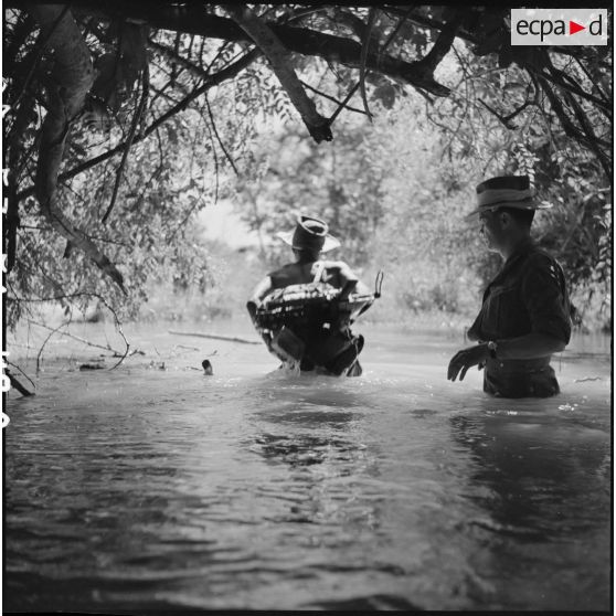 8 à 11 Progression des militaires du commando dans un petit cours d'eau, avec de l'eau jusqu'à la ceinture. [description provisoire]